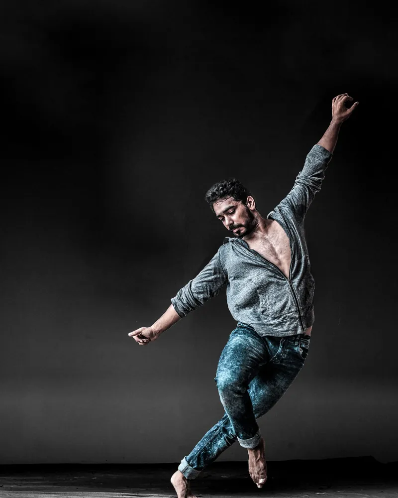 Figura en pleno movimiento de danza contemporánea dentro de una sala de ensayo en penumbra